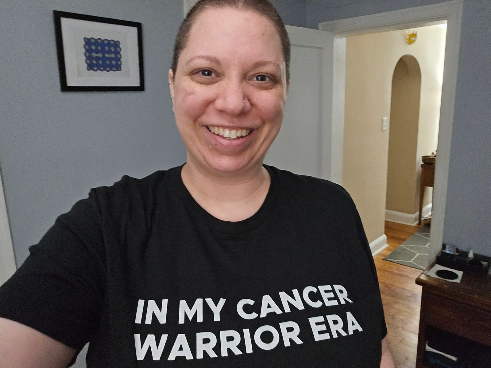 Ashe wearing a black, minimalist cancer t-shirt they designed that says "In my cancer era."